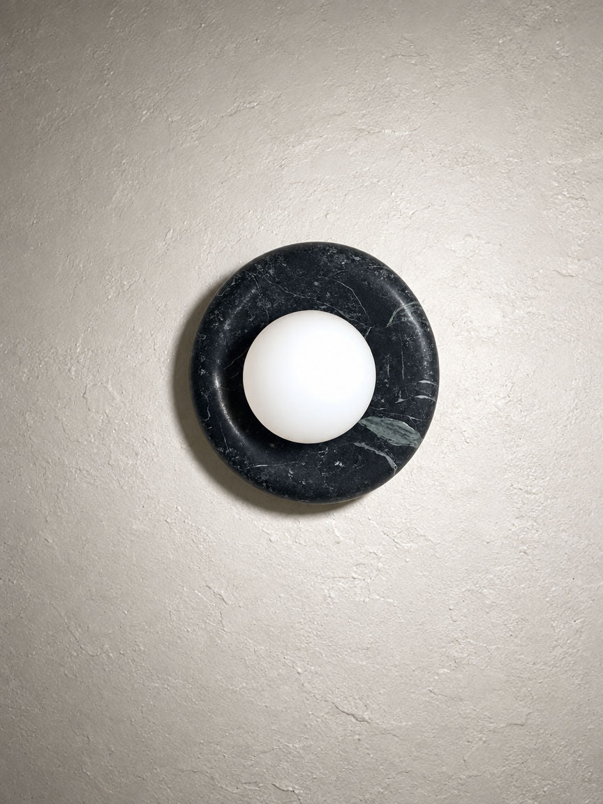 Orba Marble Wall Sconce in Nero on a plaster wall